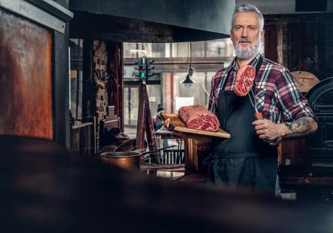 Confident old chef posing in in stylish meat grocery Stock Photos