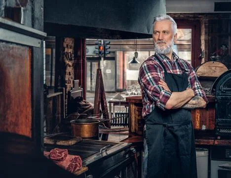 Confident old man posing in meat grocery in vintage style Stock Photos