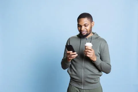 Confident optimistic man browsing his smartphone and serving coffee Stock Photos