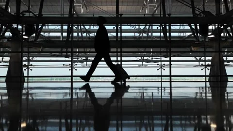 Confident passenger walking through an empty terminal with a carry-on suitcase Stock Footage 186413643