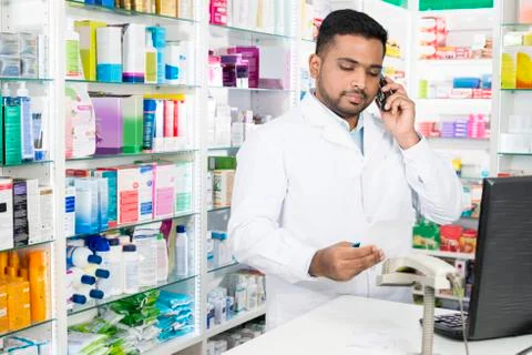 Confident Pharmacist Using Phone While Holding Prescription Pape 写真素材