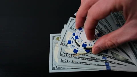 Confident places chips on stack of dollars bills. Man raises the bets in a Stock Footage 262614551