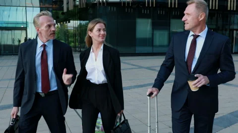 Confident professionals pulling suitcase in the modern business centre Stock Footage 134414702