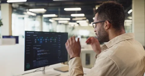 Confident programmer adjusts glasses reviewing code on computer in modern office Stock-Footage 346983553