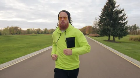 Confident red-bearded man running along bicycle path in the bosom of nature Stock Footage 255332322