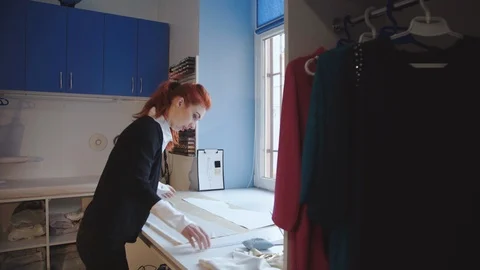 Confident seamstress drawing pattern outline on tissue in atelier Stock-Footage 105243364