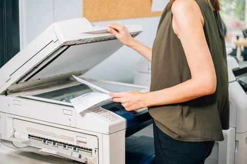 Confident secretary using modern printer and working at company Stock Photos