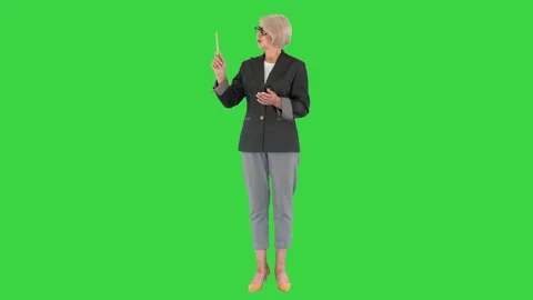 Confident senior lady teacher explaining and pointing at something on a Green Stock Footage 138542448