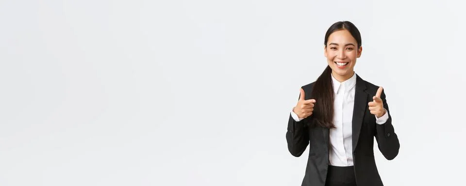 Confident smiling asian saleswoman in black suit showing thumbs-up, guarantee Stock Photos