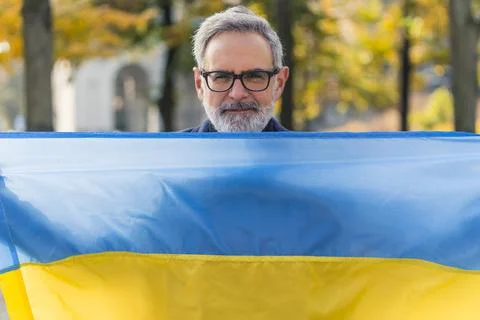 Confident, smiling, middle-aged, bearded, grey-haired man holding the blue-and Stock Photos