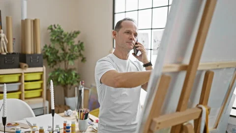 Confident, smiling middle-aged man artist engaging on his smartphone, cheer.. Stock Footage 254761625