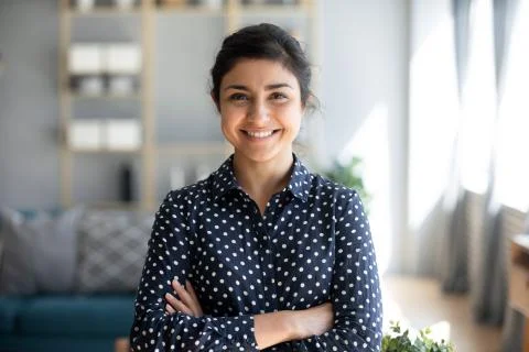 Confident smiling millennial indian woman standing with folded arms. Stock Photos