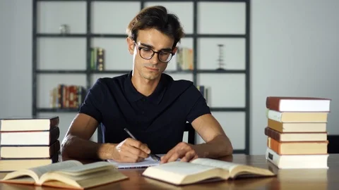 Confident Student doing his homework. Writting in notebook, reading in the Stock Footage 93248876
