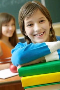 Confident student looking at camera with stack of books 스톡 사진