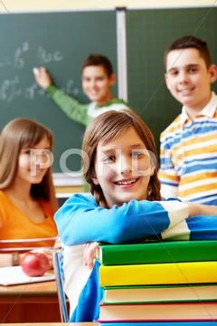 Confident student looking at camera with stack of books Stock Photos