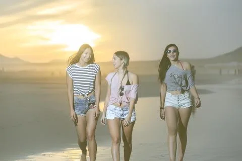 Confident trendy models walking on beach Stock Photos