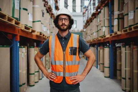 Confident warehouse manager standing in between shelf with hands on waist Stock Photos