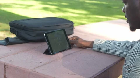 A Confident Worker Uses Tablet for Call in a Peaceful Outdoor Workspace. Stock Footage 308671075