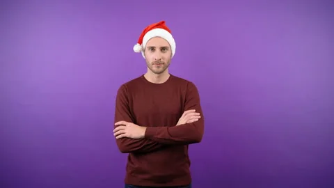 Confident young attractive bearded man in christmas santa hat with folded hands Stock Footage 142893473