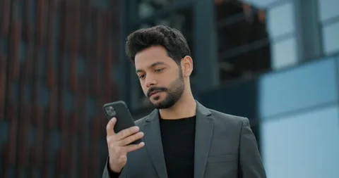 Confident young businessman smiling while using a smartphone. Stock Footage 244512499