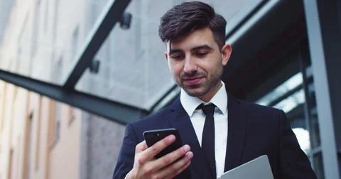 Confident young businessman using smartphone outside modern office building Stock Footage 140109142