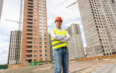 Confident young construction engineer posing against building site Stock Photos