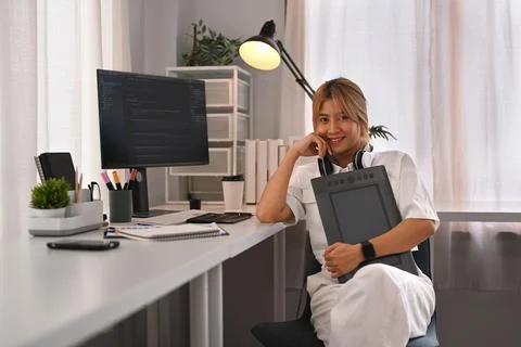 Confident young female website developer sitting front of computers with coded 스톡 사진