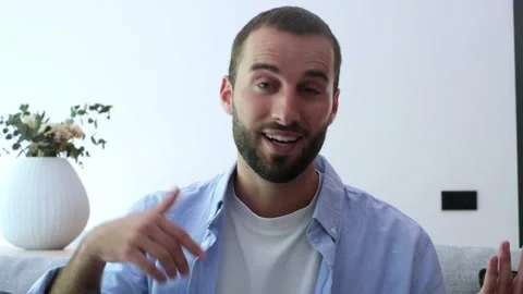 Confident young man with a beard waving his hand and speaking directly Stock Footage 345078935