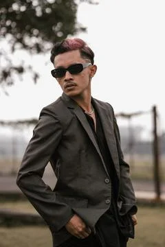 Confident young man in dark jacket and sunglasses outdoors Stock Photos