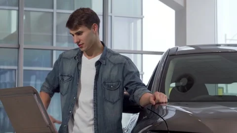 Confident young man exploring options at a car dealership Stock Footage 311541706