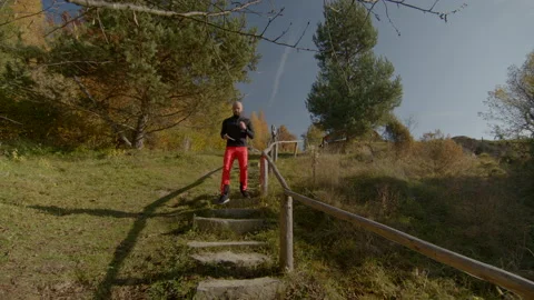 Confident young man jogging down the stairs in autumn. Low angle view. Clear Stock Footage 167336670