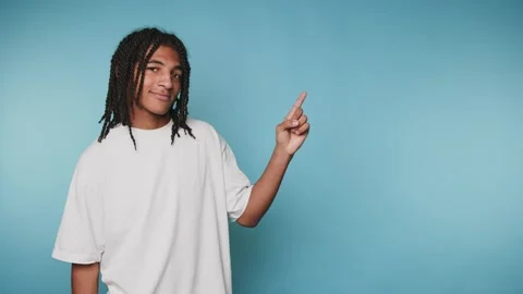 Confident young man points upward with a friendly smile, conveying positivi.. Stock Footage 313279977