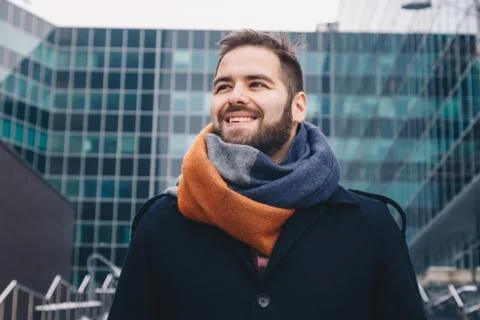 Confident young man posing in front of a modern day building. Stock Photos