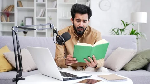 Confident young man recording audiobook or podcast using laptop and microphone  Stock Footage 252215089
