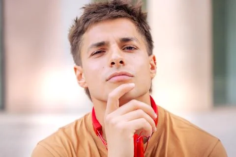 Confident young man with thoughtful expression and headphones around his neck. Stock Photos
