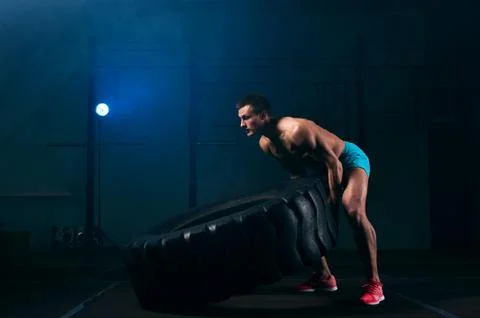 Confident young man working out with tire in gym Stock Photos