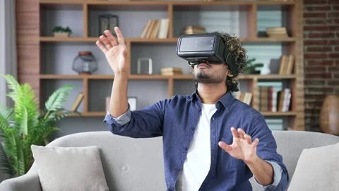 Confident young man works using VR glasses in virtual reality simulator sitting  Stock Footage 297876736