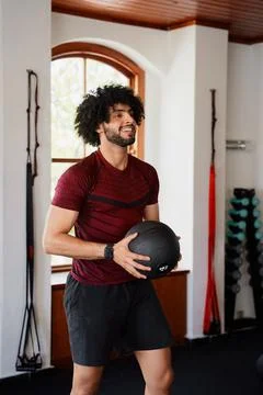 Confident young middle eastern man with medicine ball at the gym Stock Photos