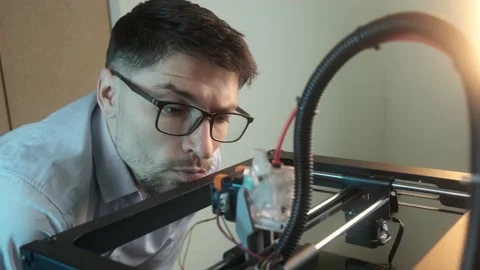 Confident young student using a 3D printer in modern college Stock Footage 236616093