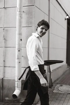 Confident young waiter smiling while carrying a tray on the job Stock-Fotos