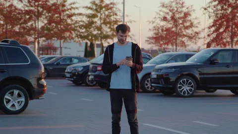 A confused and scared young man in an open-air parking lot outside on a Video stock 314309060
