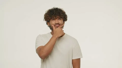 Confused brunette man posing in studio. Front view of bewildered guy rubbing Stock Footage 231901928