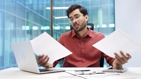 Confused businessman in glasses having difficulty with paper work sitting  Stock Footage 288880890
