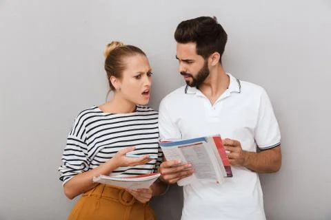 Confused displeased shocked young loving couple friends man and woman indoors Stock Photos