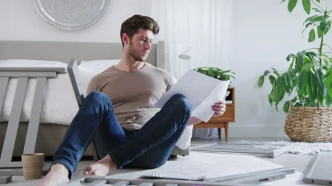 Confused Father To Be Looking At Instructions For Self Assembly Baby Cot Stock Footage 130903007