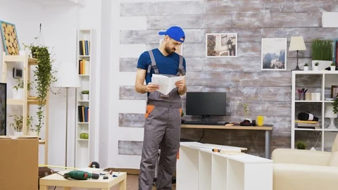 Confused furniture assembly worker while reading instructions Stock Footage 123343161