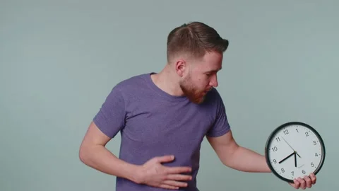 Confused man with anxiety checking time on clock, running late to work, being in Stock Footage 170633460