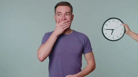 Confused man with anxiety checking time on clock, running late to work, being in Stock Footage 170633484