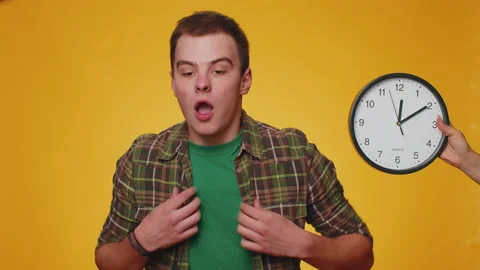Confused man with anxiety checking time on clock, running late to work, being in Stock Footage 218025254