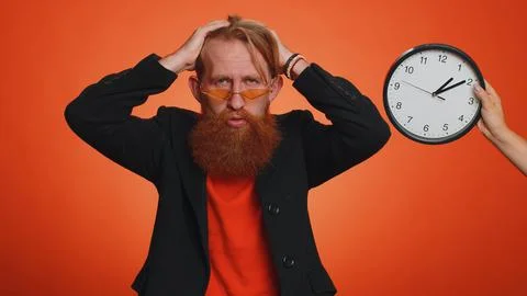 Confused man with anxiety checking time on clock, running late to work, being in Stock Photos